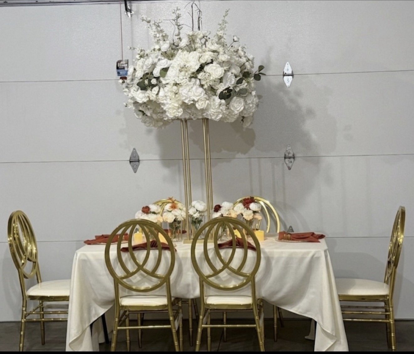 Elegant table setup with gold phoenix chairs and tall white floral centerpiece